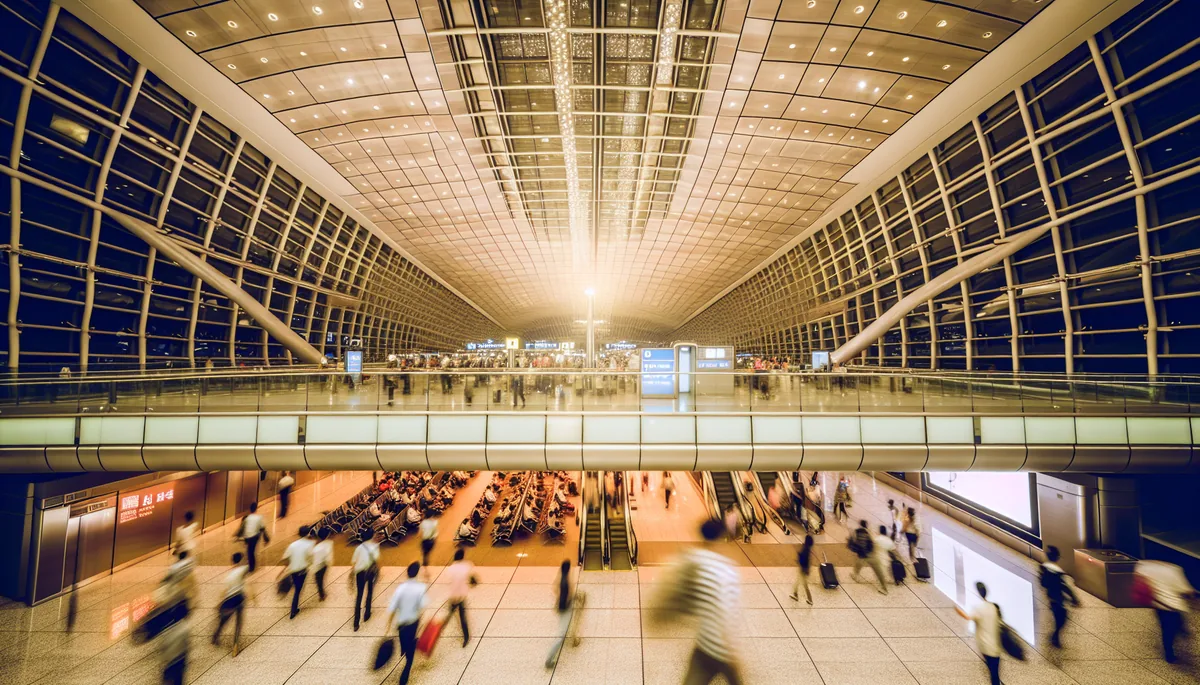 Busy international airport terminal with travelers walking through modern glass corridors and departure gates